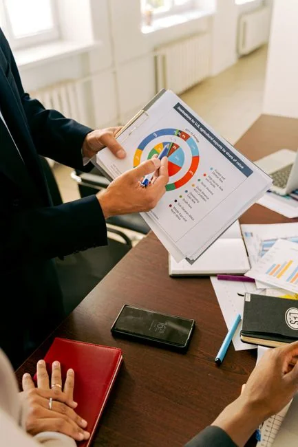 Overhead view of e-commerce chart with smartphone calculator and magnifying glass on a table.